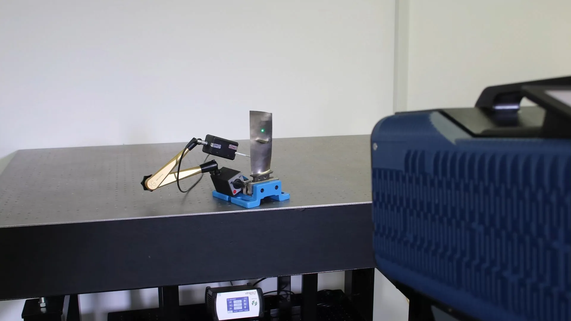 Eingespannte Turbinenschaufel mit automatisierter Modalhammer-Anregung im Laser-Vibrometrie-Messaufbau.